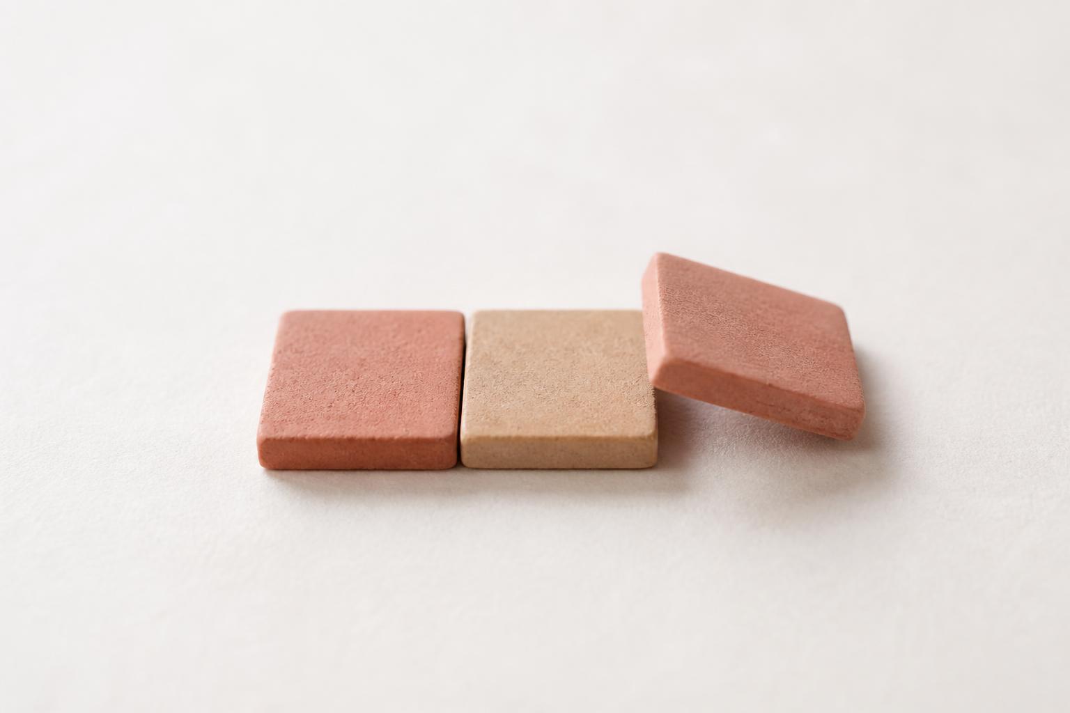 Close-up of three tactile tiles being lined up on paper, with one tile lifted at an angle.